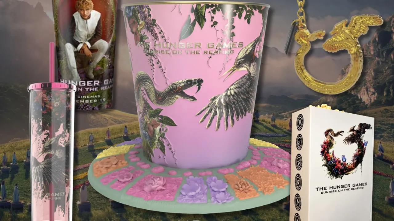 The Sunrise on the Reaping cinema collectables: a pink popcorn tub with a snake and mockingjay on a base of moulded flowers, a Haymitch cup, a pink tumbler, a gold key chain and a white districts tin.