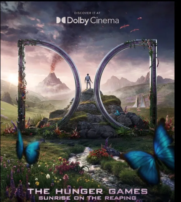 The Dolby Cinema poster: Haymitch on a hilltop between two mirrored Dolby arches, the volcano smoking to the left, blue butterflies in the foreground