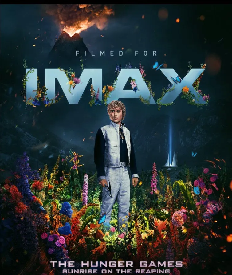 The Filmed for IMAX poster: Haymitch waist-deep in wildflowers, the IMAX lettering overgrown with blooms and butterflies, the volcano smoking behind him